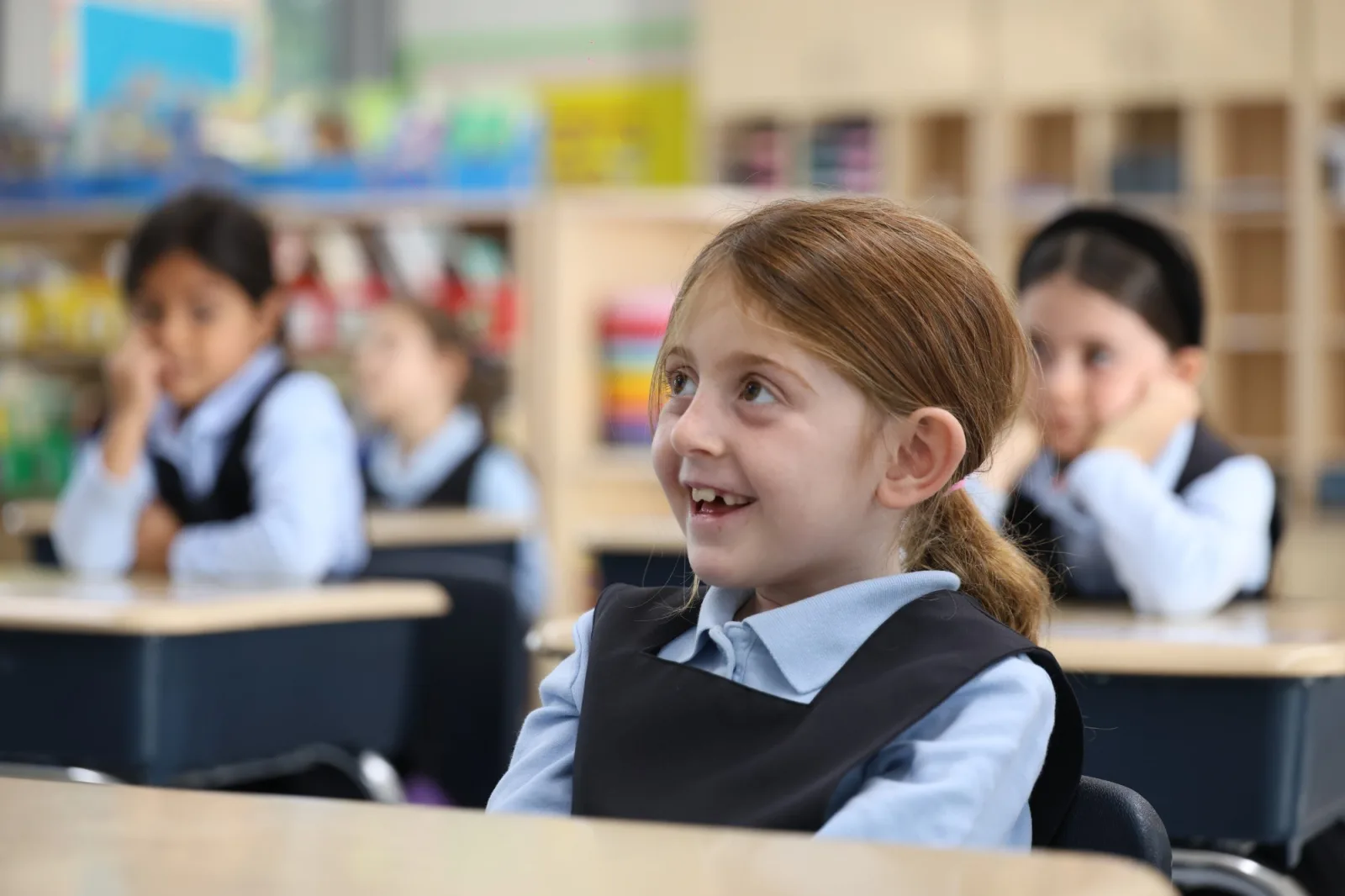 A girl in uniform smiling in her classroom
